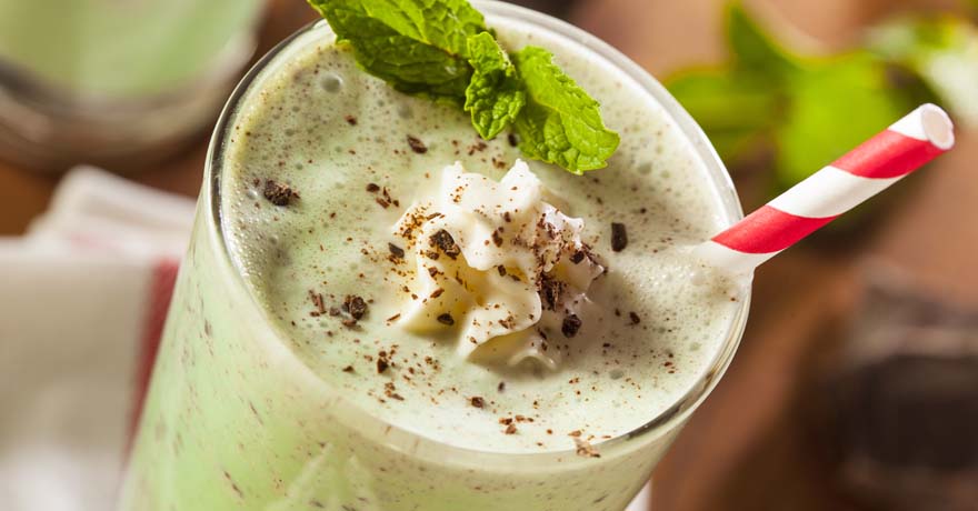 Chocolate mint shake with whipped cream in a glass cup and  candy cane striped straw