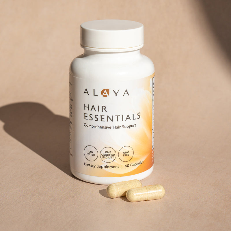 Alaya Hair Essentials supplement bottle with capsules on a beige background